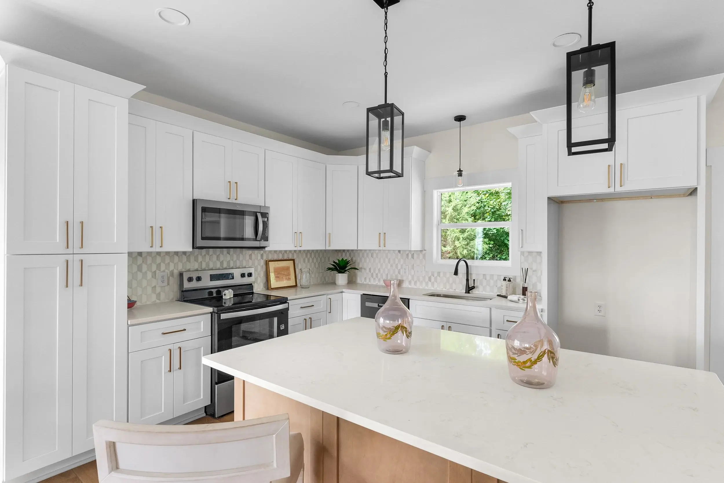 White kitchen with large island and hanging lights.